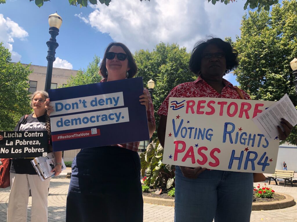 Julie Archer and Pam Garrison taking action, holding protest signs in support of the Voting Rights Act. Featured image to Capital Eye V12 N10